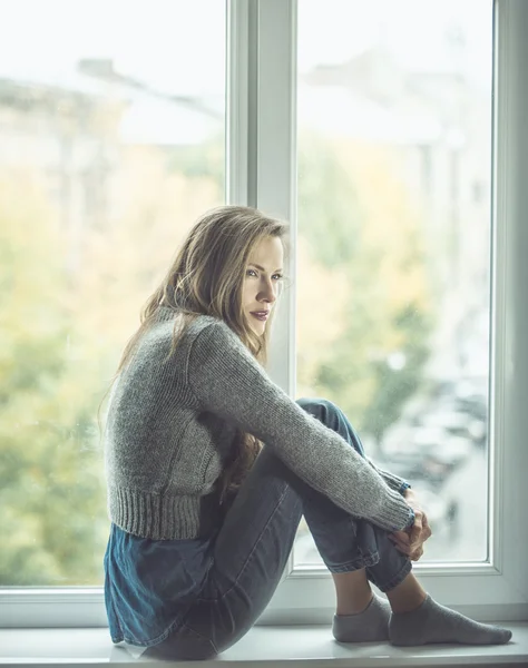 Belle jeune femme assise près de la fenêtre — Photo