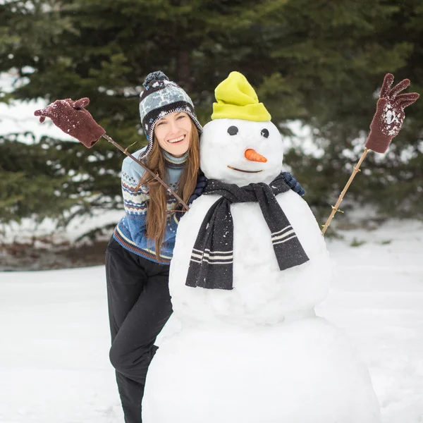 Mulher de inverno engraçado bonito com boneco de neve — Fotografia de Stock