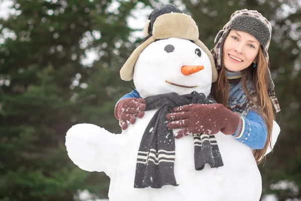 Hermosa mujer divertida de invierno con muñeco de nieve — Foto de Stock