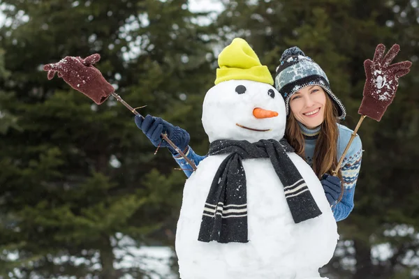 Mulher de inverno engraçado com boneco de neve — Fotografia de Stock