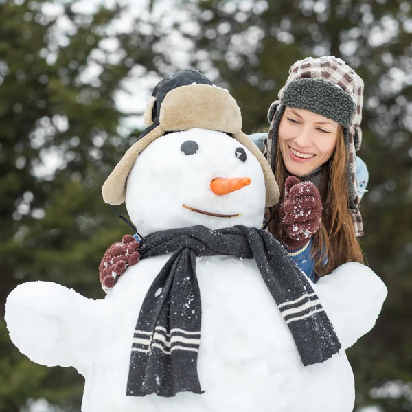 Mulher de inverno engraçado com boneco de neve — Fotografia de Stock