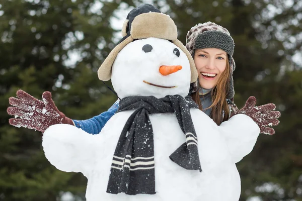 Mulher de inverno engraçado com boneco de neve — Fotografia de Stock