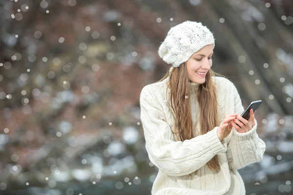 Junge Frau lächelt mit Smartphone — Stockfoto