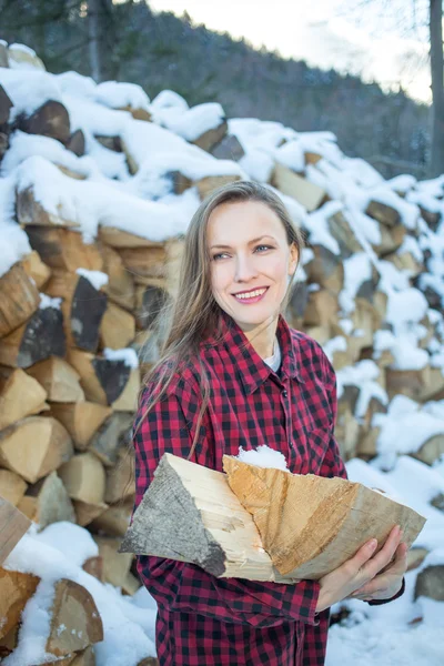 Ung kvinna poserar med trä loggar för brasa — Stockfoto