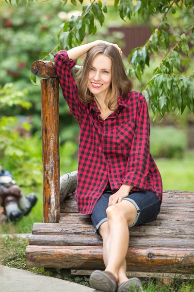 Yeşil bahçe çim üzerinde oturan genç kadın — Stok fotoğraf