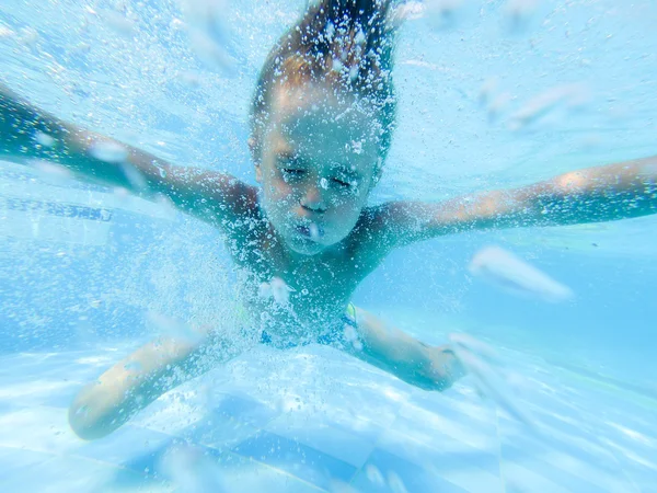 Cute boy swimming underwater in pool