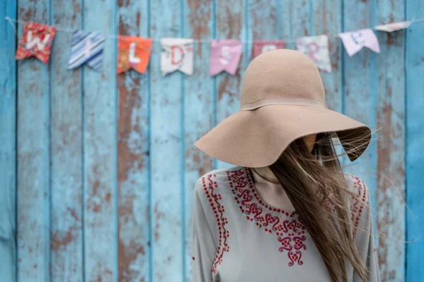 Jonge vrouw met hoed tegen blauwe houten muur — Stockfoto