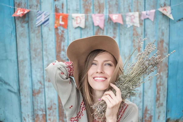 Jeune femme avec chapeau contre mur en bois bleu — Photo