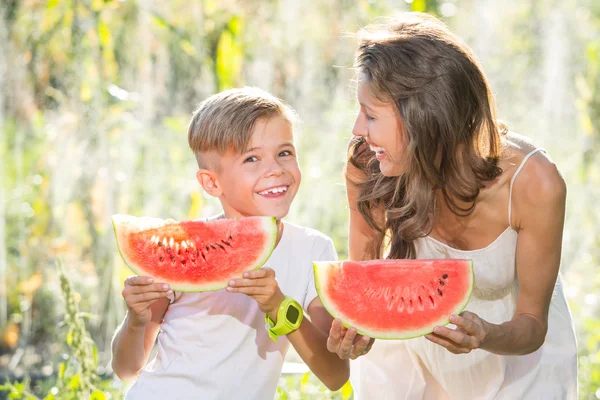 Glücklich lächelnde Familie isst Wassermelone im Park — Stockfoto