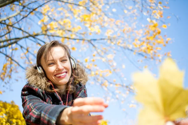 Beautiful girl listening to music in autumn landscape golden park and blue sky — Stock Photo, Image