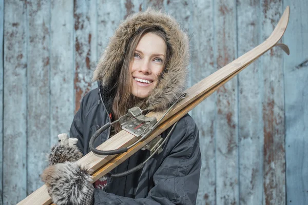 Vacker kvinna med retro skida över vintage trävägg — Stockfoto