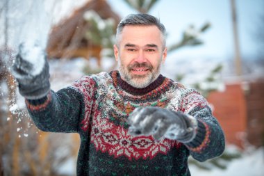 Kış eğlence adam mutlu gülümseyerek ve kartopu atarak
