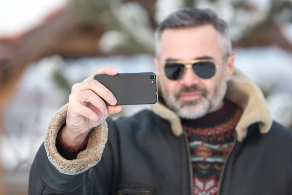 Bonito homem tirar uma foto de si mesmo com um smartphone — Fotografia de Stock