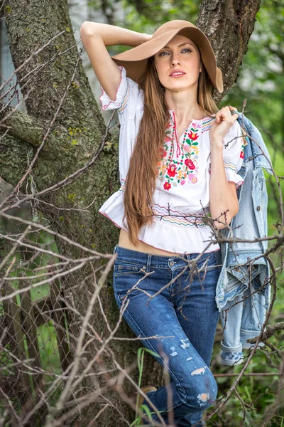 Lente vrouw in wilde tuin staande tegen oude boom — Stockfoto