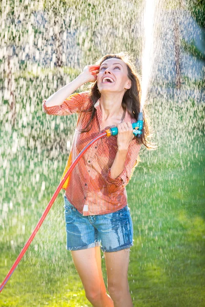 Ung sexig kvinna ha roligt medan vattning en trädgård — Stockfoto