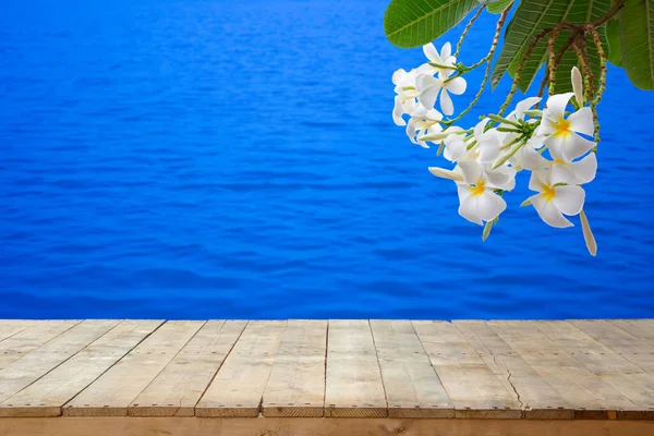 Vintage style wooden flooring for the background to place products with beautiful white plumeria flowers, consisting of a blue water-based backdrop, out of focus for products that offer freshness.