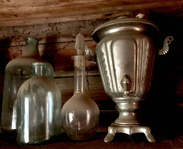 Vintage anciennes bouteilles poussiéreuses décanteur samovar, toile d'araignée dans une vieille maison abandonnée, sur un fond en bois. — Photo