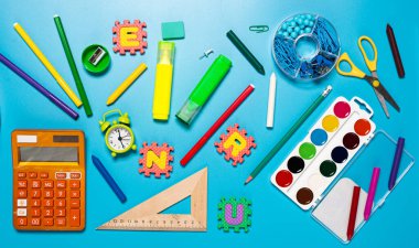 Çalar saat, boya, kalemler ve mavi arka plandaki diğer okul eşyaları. Düz konum kırtasiyesi