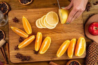 Kadın elleri portakal dilimliyor, narenciye kesiyor. Bıçak, tahta kesme tahtası, meyve sıkacağı, yakın plan. Ev yapımı limonata yapıyorum.