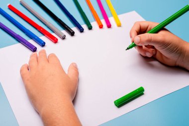 Küçük çocuk masaya tebrik kartı çiziyor. Aile Günü konsepti