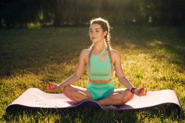 Parkta yoga yapan güzel bir genç kadın.