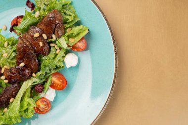 Tavuklu sıcak salata, fırında balkabağı, kiraz domatesleri ve ahşap masadaki seramik tabakta salata karışımı. Seçici odak