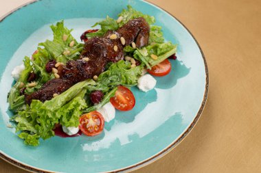 Tavuklu sıcak salata, fırında balkabağı, kiraz domatesleri ve ahşap masadaki seramik tabakta salata karışımı. Seçici odak