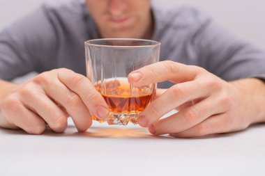 Gömlekli adam elinde şişe ve bir bardak viski tutuyor.