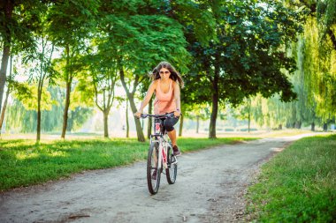 Orman yollarında bisiklet süren güzel kız.