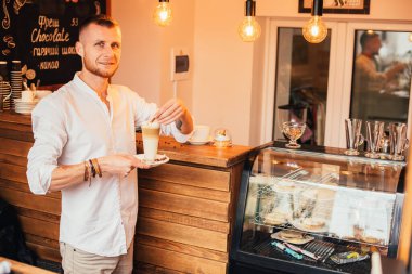 Adam kahvecide latte içiyor.