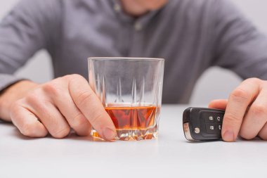 İçkili araba kullanma, uzaktan kumandalı araba anahtarı ve bir bardak viskisi olan adam.