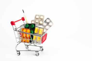 İlaç alışverişi, sağlık giderleri ve reçeteli ilaç konsepti için alışveriş arabası ya da mavi arka planda bulunan ve fotokopi alanı ile izole edilmiş haplarla dolu tramvay