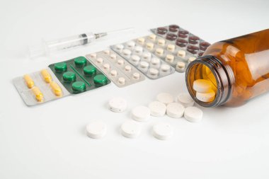 çok renkli sarı, turuncu, kahverengi haplar ve beyaz arka planda tıbbi şırınga