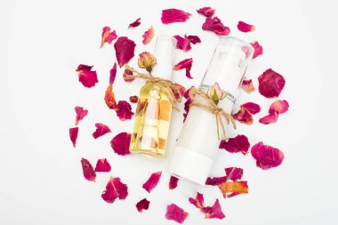 Beyaz arka planda küçük güllerle süslenmiş doğal kozmetik ürünleri olan şişeler..