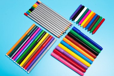 mavi arkaplandaki farklı renkli kalemler ve kalemler