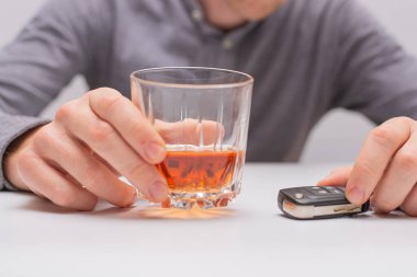 İçkili araba kullanma, uzaktan kumandalı araba anahtarı ve bir bardak viskisi olan adam.