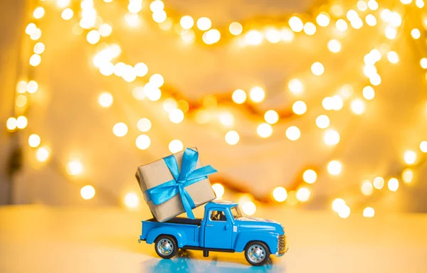 blue retro toy car delivering Christmas or New Year illuminated tree on festive background