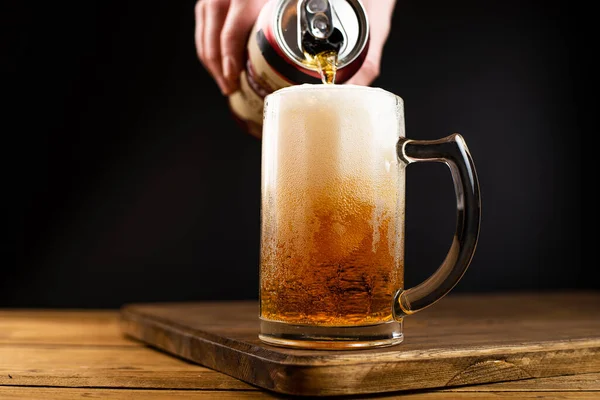 hand pours beer from a can into a glass