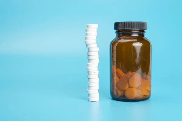 medicine pills in glass jar on blue background