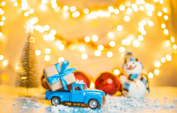 blue retro toy car delivering Christmas or New Year illuminated tree on festive background