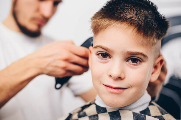 barber grooming cute little boy at hair salon