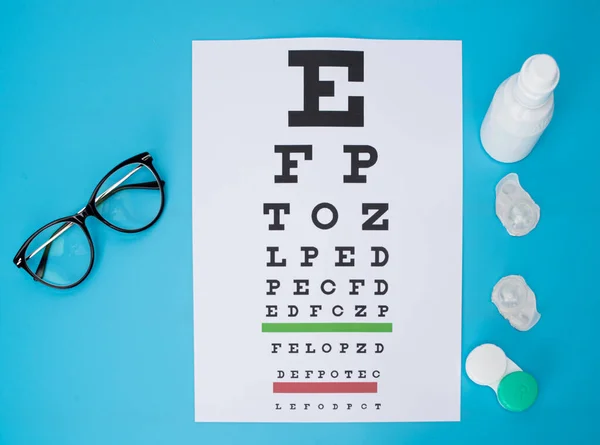 glasses and contact lenses in containers, on snellen eye chart background