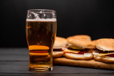 Bira bardağı, ahşap arka planda çizburger.