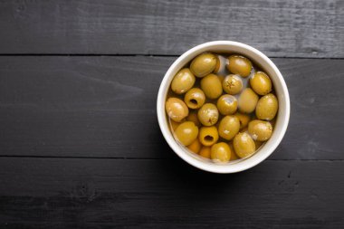 Ahşap arka planda marine edilmiş zeytinler.