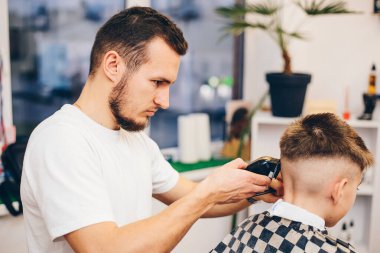 Berber kuaförde küçük şirin bir çocuğu tımar ediyor.