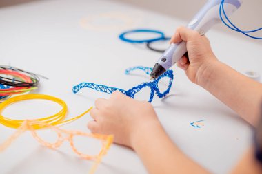 3D yazdırma kalemi olan odaklanmış çocuk oyuncak yaratıyor