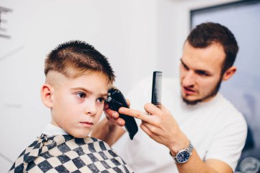 Berber kuaförde küçük şirin bir çocuğu tımar ediyor.