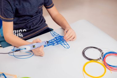 3D yazdırma kalemi olan odaklanmış çocuk oyuncak yaratıyor