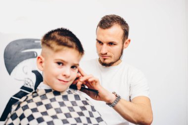 Berber kuaförde küçük şirin bir çocuğu tımar ediyor.