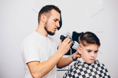 Berber kuaförde küçük şirin bir çocuğu tımar ediyor.